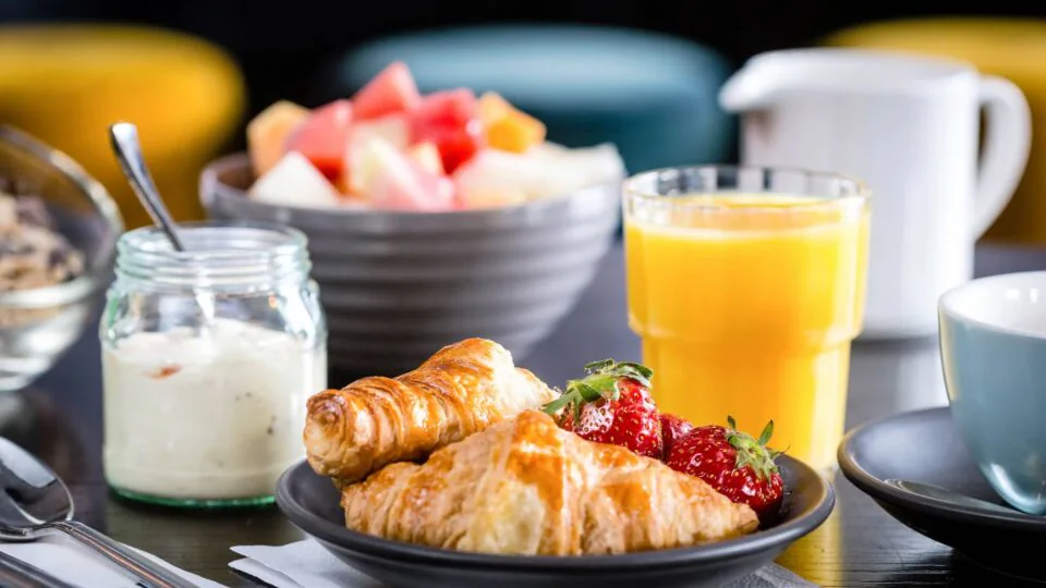 Delicious hotel breakfast with fresh croissants, strawberries, yoghurt, orange juice, and a colourful fruit bowl.