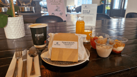Enjoy a complimentary breakfast with coffee, juice, muffins, yoghurt, and fruit in a cosy, welcoming hotel dining area.