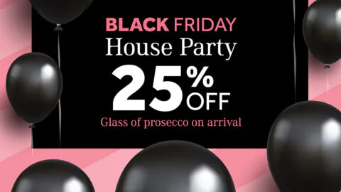 Black Friday House Party promotion sign with black balloons, offering 25% off and a complimentary glass of prosecco on arrival against a pink striped background.